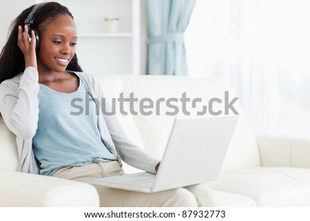 Smiling woman listening to music while using her notebook