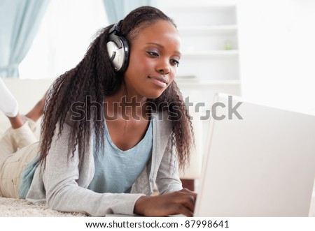 Close up of young woman lying on the floor with her notebook enjoying music
