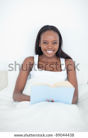 Portrait of a young woman holding a book in her bedroom