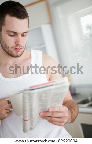 Portrait of a man drinking orange juice while reading the news in his kitchen