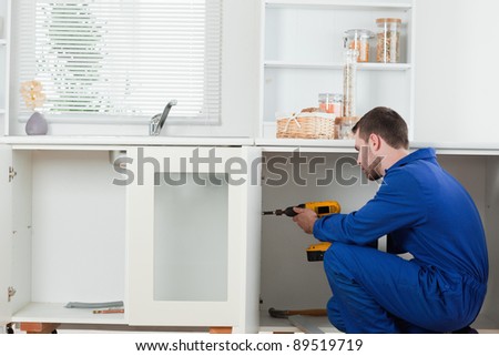 Good looking handyman fixing a door in a kitchen