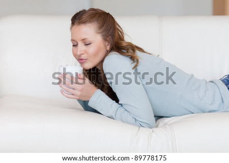 Relaxed young woman enjoying a coffee break on the sofa