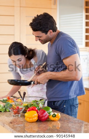 Portrait of a young couple cooking with a pan in their kitchen