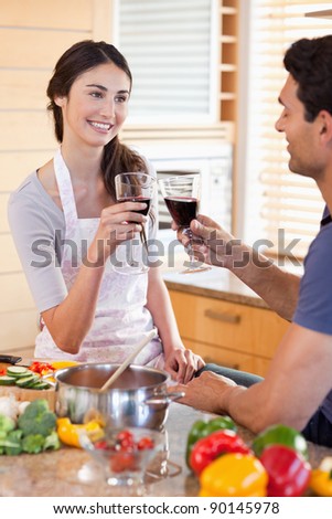 Portrait of a young couple having a glass of wine while cooking in their kitchen