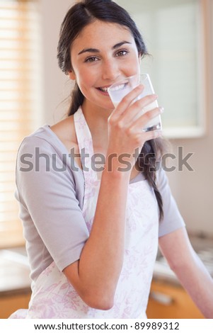 Portrait of a gorgeous woman drinking milk in her kitchen