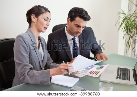 Sales persons working with a notebook in an office