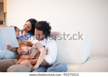 Young family in the living room looking at photo album together
