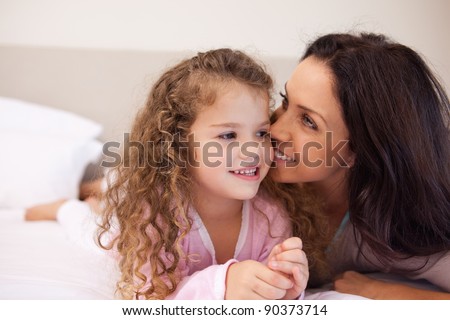 Young mother whispering into her daughters ear