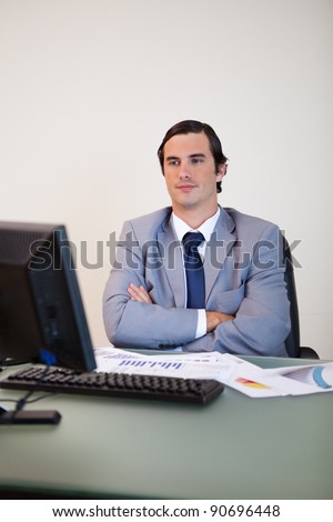 Businessman with arms folded waiting for his computer to boot up