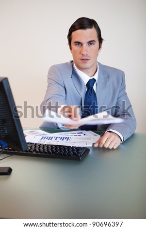 Businessman at his desk handing over contract