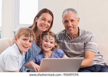 Happy family sitting on a couch using a laptop in a living room