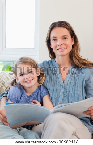 Portrait of a mother reading a book to her daughter in a living room
