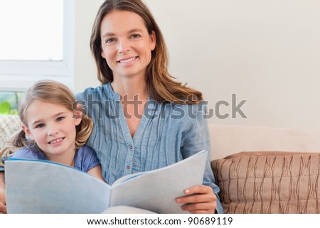 Happy mother reading a book to her daughter in a living room