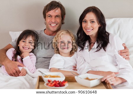 Happy family having breakfast together in a bedroom