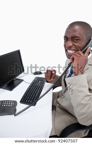 Side view of a businessman answering the phone while using a monitor against a white background