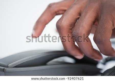 Close up of a masculine hand taking a phone handset against a white background