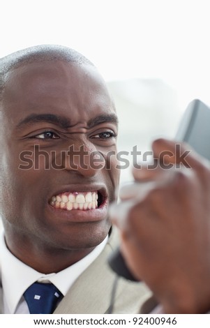 Portrait of an angry businessman looking at his phone handset in his office