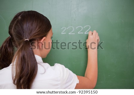 Girl writing numbers on a blackboard