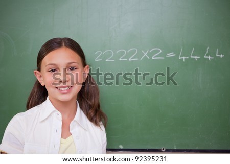 Schoolgirl posing in front of a chalkboard in a classroom