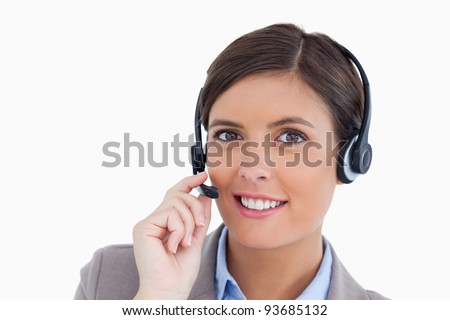 Close up of smiling female call center agent adjusting her headset against a white background