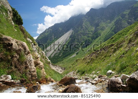 Mountain landscape in clear summer day. Mountain river in the foreground