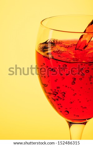 Pouring red wine into a glass on a yellow background
