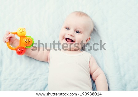 smiling baby boy with toy on background