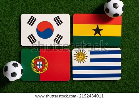 World football champion in Qatar. Group H. Flag badges depicting the national teams of South Korea; Ghana; Uruguay; Portugal. Top view on the field and classic balls from the side. Stock fotó © 