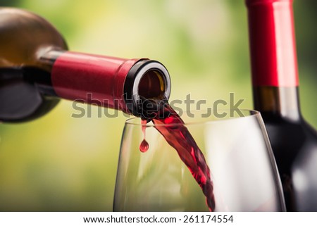 Poured red wine into glass on natural background