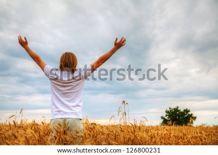 Young man staying with raised hands at sunset time