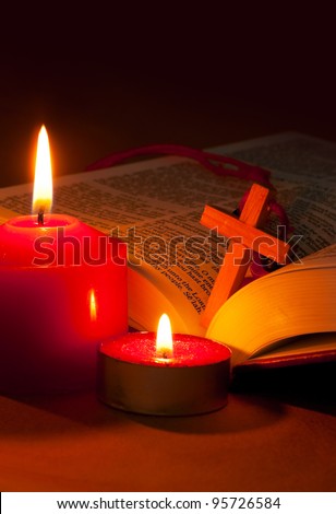 Open Bible with cross and burning red candles