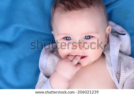 Blue Eyed Baby Boy on a Blue Blanket Chewing on His Fingers