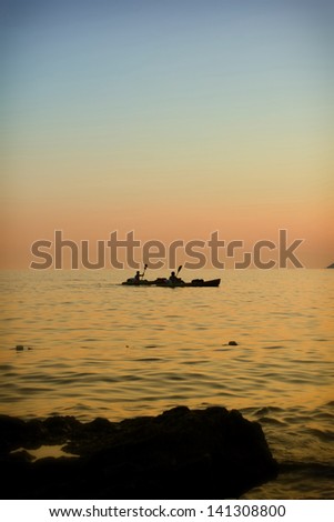 Two persons in kayaks on the sea at sunset as symbol of balance in life