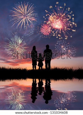The happy family looks beautiful colorful holiday fireworks in the evening sky with majestic clouds