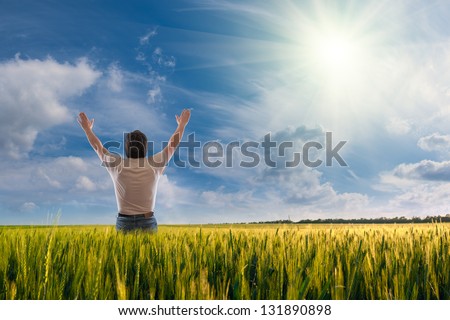 A man standing with open arms, sun in the sky, feeling of freedom