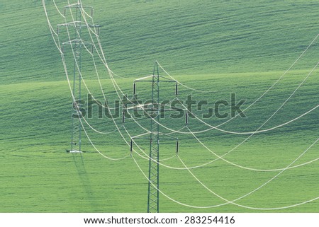 High-voltage power line on background of green field of wheat