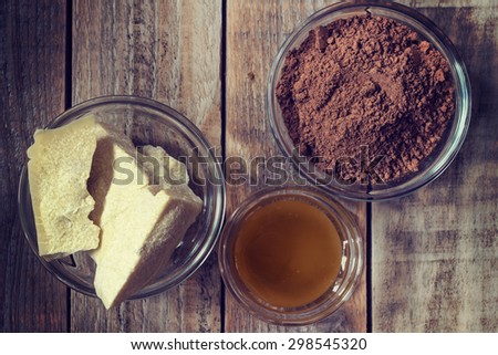 Close up image of ingredients of chocolate: cocoa butter, cocoa powder and honey on grunge wooden background