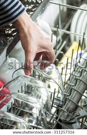 Close up of hand picking clean dishes from dish washer