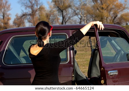 Woman standing in front of old, dirty four wheel car talking on a cell phone
