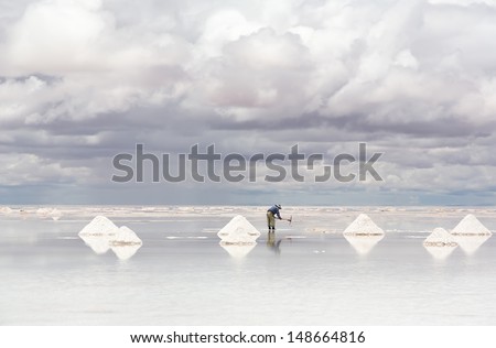 Worker performing harvesting salt on the salt lake Salar de Uyuni, Bolivia