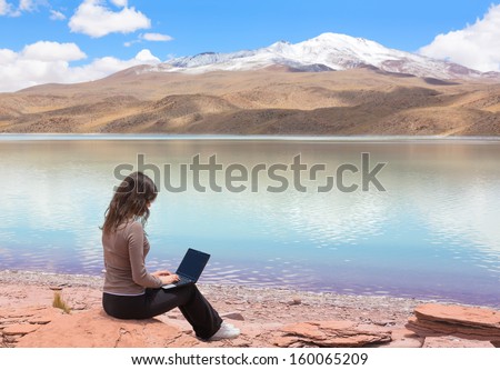 Woman with laptop on the shore of mountain lake Laguna Celeste, Bolivia