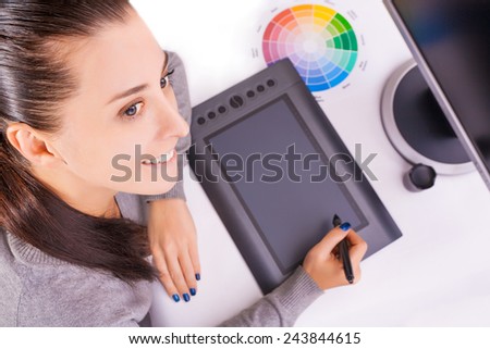 Female graphic designer working in office using tablet pen, selective focus