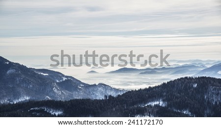 Hiking in the winter hills and mountains. Outdoor activity on a clear and sunny day. Vast forests and meadows covered with snow. Dramatic scenery in the Julian Alps.
