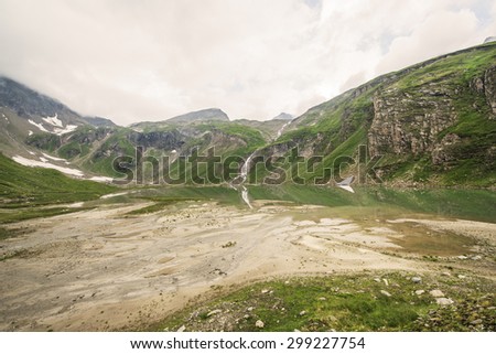 Waterfall and Snowmelt in the Hohe Tauern national park in Austria below the Grossglockner glacier. Cloudy and misty day on a summer day in Tirol.