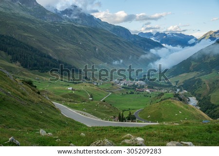 Road to Furka mountain pass in Switzerland just after the storm. Foggy and cloudy conditions with epic view in the back.