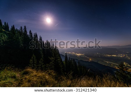 Night on the mountain with stars at full moon. View of the valey and towns at night.