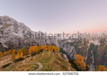 Beautiful autumn panorama in Julian Alps. Larches are glowing in golden yellow color at Slemenova Spica under Jalovec mountain.