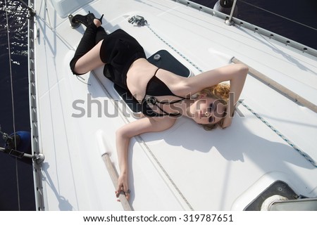 The beautiful young girl, in thigh high leather boots on the yacht