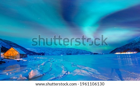 Northern lights (Aurora borealis) in the sky over Tromso, Norway - Aurora reflection on the sea on the background Norwegian fjord - Winter season.