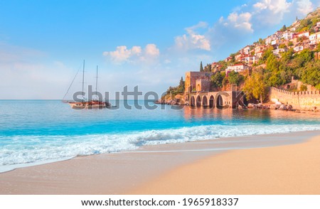 Beautiful sandy beach and soft turqoise Mediterranean sea wave - Landscape of ancient shipyard near of Kizil Kule tower - Alanya peninsula, Turkey